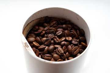 Freshly roasted fresh aromatic coffee beans in a coffee grinder on a white background, ground coffee, making coffee