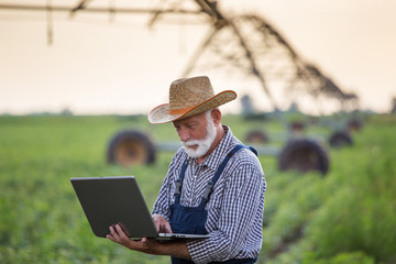 Sticker - Farmer with laptop in front of irrigation system in field