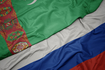 waving colorful flag of russia and national flag of turkmenistan.