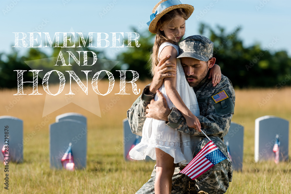 military father in uniform hugging child near headstones in graveyard ...