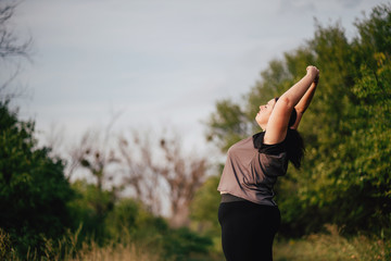Body positive, yoga, confidence, high self esteem, meditating. Young calm overweight woman doing yoga at summer meadow. obesity, wellness, outdoor activity and health.