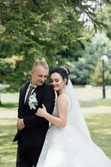 Wall Mural - Amazing smiling wedding couple. Pretty bride and stylish groom. Beautiful couple bride and groom. Young wedding couple enjoying romantic moments outside city