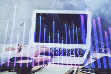 Forex graph with businessman working on computer in office on background. Concept of hardworking. Double exposure.