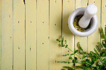 Wall Mural - mint and mortar, pestle on yellow wooden background, top view emty space