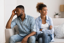 Upset Black Couple Avoiding Eye Contact Sitting On Couch