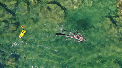 Wall Mural - Aerial drone top view photo of spear fishing diver in tropical exotic emerald sea