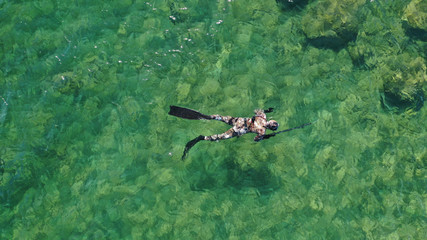 Aerial drone top view photo of spear fishing diver in tropical exotic emerald sea