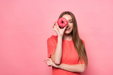 front view of smiling attractive young woman holding sweet doughnut and looking at camera on pink