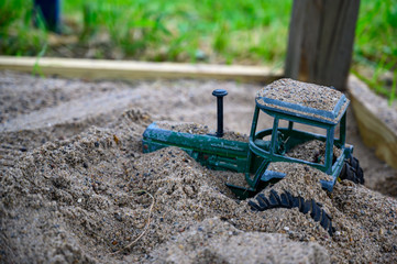 Vintage metal tractor buried in sandbox