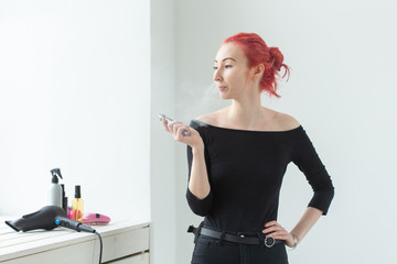 Vape, addiction and people concept - young woman with colored hair is smoking a vape