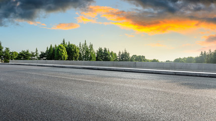 Country asphalt road and green woods nature landscape at sunset