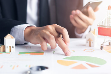 Hands of businessman holding smartphone working analyzing financial documents, Financial concept