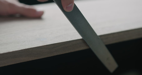 woodworker hand sanding walnut board with file