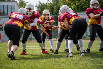 Full-length photo of sportswomen playing american football on green lawn