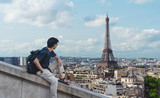 Fototapeta Paryż - a man with backpack looking at Eiffel tower, famous landmark and travel destination in Paris, France