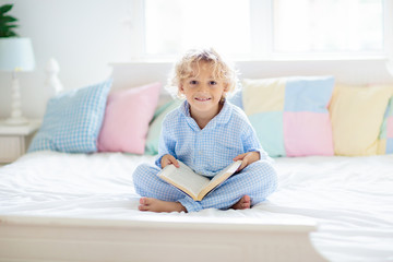 Wall Mural - Child reading book in bed. Kids read in bedroom.