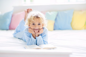 Wall Mural - Child reading book in bed. Kids read in bedroom.