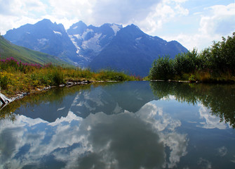 alpine lake in the botanic garden of le col du lautaret with eastern face of the summit called 