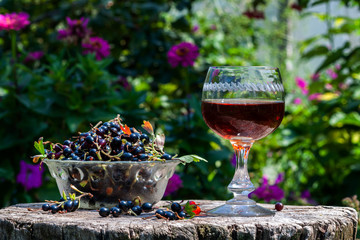 Blackcurrant wine with berries in avza glass from an old wooden table