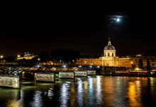 Institut De France And People Walking On Pont Des Arts At Night - Paris, France.