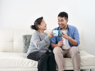 Wall Mural - Asian mother and her son talking and drinking at home, lifestyle concept.