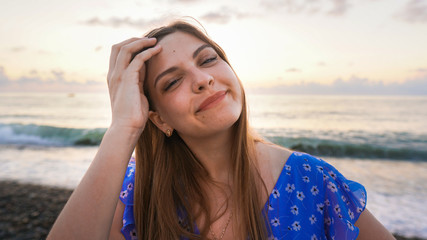 Outdoors lifestyle fashion portrait stunning young girl enjoying on beach on the tropical island and laughing. In the background the sea. Wearing stylish blue dress. Straight long hair