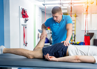 Wall Mural - Rehabilitation therapy. Physiotherapist working with young male patient in the rehabilitation center