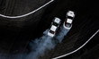 Aerial top view two cars drifting battle on asphalt race track with lots of smoke from burning tires, Two race cars competition drift battle view from above.