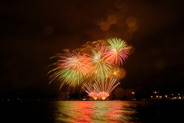 Beautiful colorful fireworks in sky over river. Big festive evening event with great pyrotechnic show.  