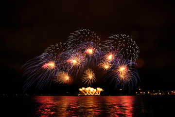 Beautiful colorful fireworks in sky over river. Big festive evening event with great pyrotechnic show.  