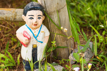 Old statue baby doll welcome to thailand in garden.