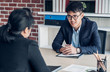 © weedezign - young asian businessman and businesswoman talking about business agreement at meeting table in modern office.business partnership concept.satisfied the deal with client negotiation