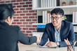 © weedezign - young asian businessman and businesswoman handshake about business agreement at meeting table in modern office.business partnership concept.satisfied the deal with client negotiation.