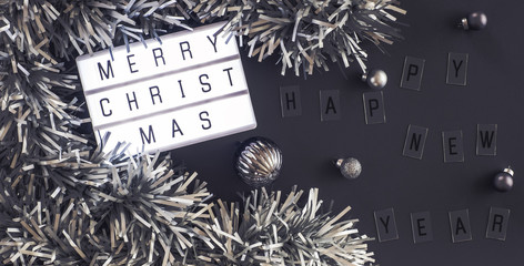 Wall Mural - Merry christmas and happy new year lightbox on black table background.top view of tinsel,ball decorate on tabletop.holiday celebration greeting card.