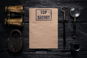 Wall Mural - top secret document mock up on a black wooden table background. blank paper sheet, binoculars, padlo
