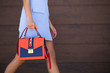 © vfhnb12 - Stylish blue with orange leather women bag. The girl holds in her hand. Young woman walking down the street with a bag. Bag close up.