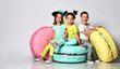 © FAB.1 - Three friends of triplets - two girls and a boy in bright clothes have fun at the birthday party fun room decoration candy macarons