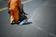Road worker using thermoplastic spray road marking machine to painting white line on asphalt street 