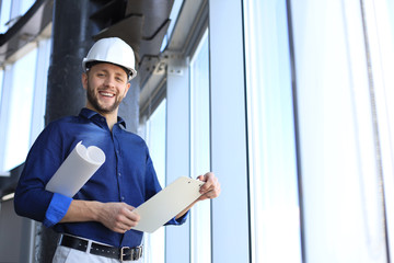 Shot of smiling male architect wearing hardhat and inspecting new building.