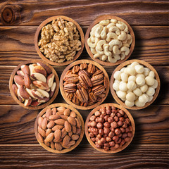 Wall Mural - various nuts in wooden bowls, top view. food background: pecan, hazelnut, walnuts, almonds, macadamia, cashew, brazil