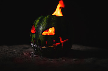 green watermelon burns with fiery flame on the scary holiday of october halloween