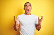 © Krakenimages.com - Young caucasian man wearing casual white t-shirt over yellow isolated background crazy and mad shouting and yelling with aggressive expression and arms raised. Frustration concept.