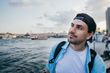 Portrait of a young man against the background of the sea and the city.