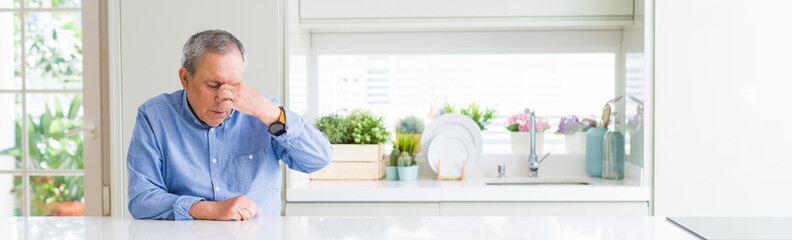 Wall Mural - Wide angle perspective of handsome senior man at home tired rubbing nose and eyes feeling fatigue and headache. Stress and frustration concept.