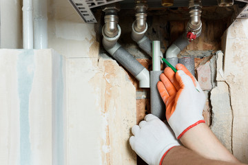 A worker is installing the gas boiler pipes.