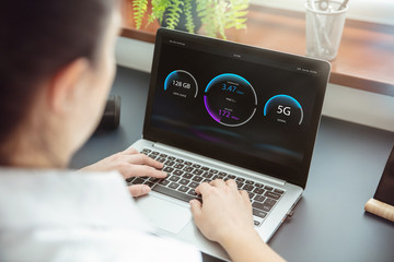 Woman checks wireless connection of 5G technology on her laptop. Interface on the screen was created in graphic program.