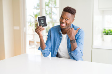 Sticker - African american man holding passport of United States of America pointing and showing with thumb up to the side with happy face smiling