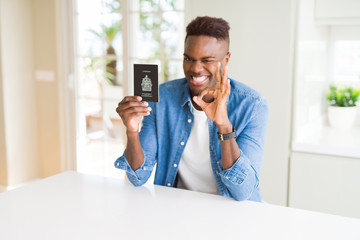 Sticker - African american man holding passport of Canada doing ok sign with fingers, excellent symbol