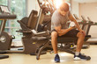 © Seventyfour - Full length portrait of muscular man lifting heavy dumbbells sitting on bench during strength workout in gym