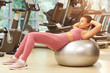 © Seventyfour - Full length portrait of beautiful young woman exercising with fitness ball during workout in gym, copy space